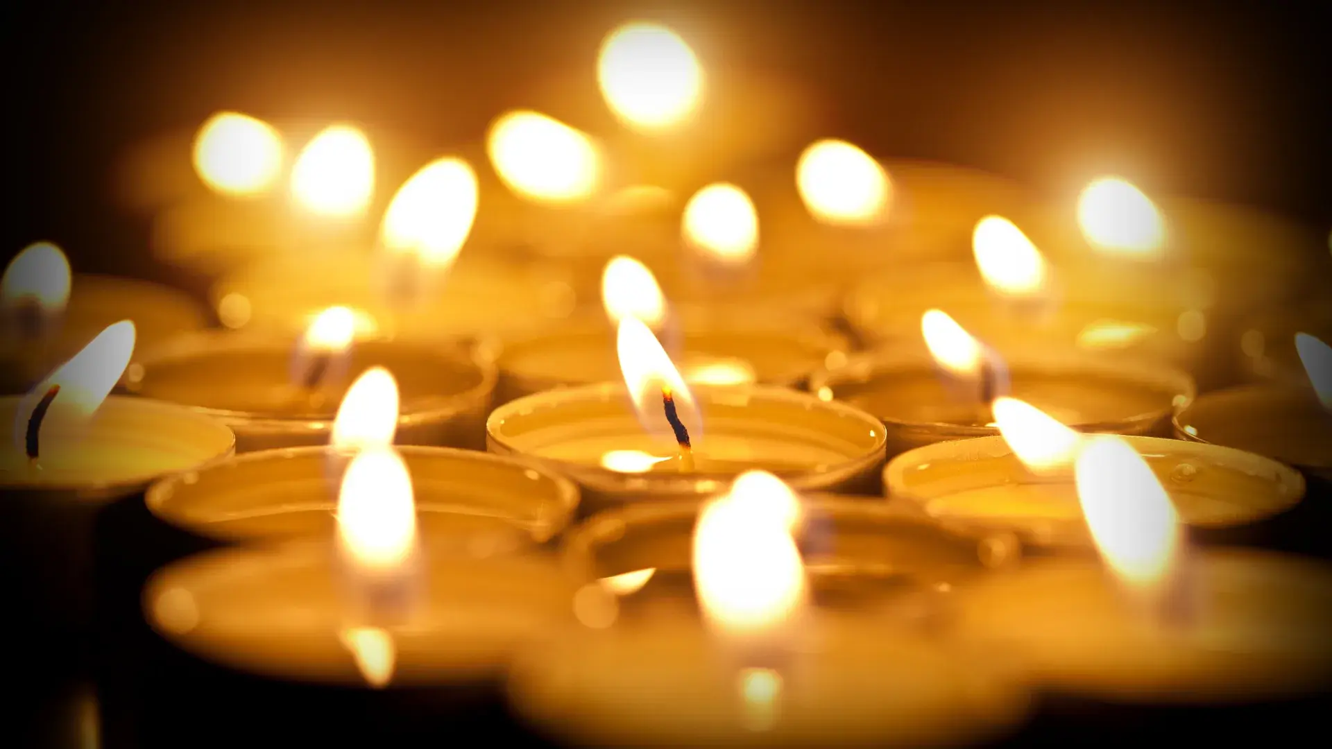 Close Up Burning Candles Against Black Background Cropped